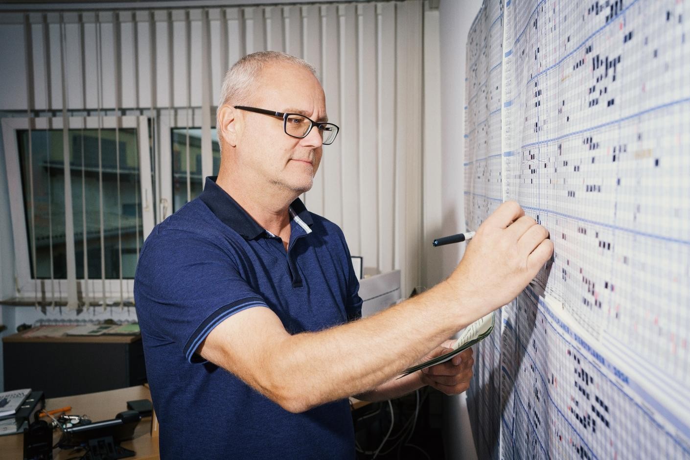 Foto: DIE KAVALLERIE GmbH Auf dem Foto ist ein Mann zu sehen, der in eine Tabelle an der Wand etwas einträgt.