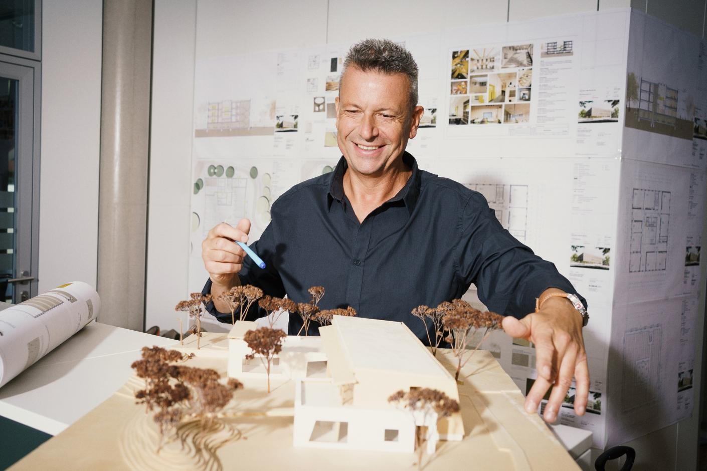 Foto: DIE KAVALLERIE GmbH Auf dem Foto ist ein Mann zu sehen, der hinter einem Modell von einem Haus steht.