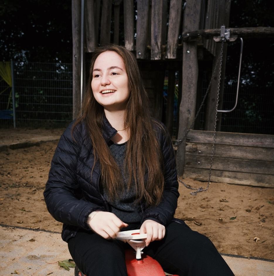 Foto: DIE KAVALLERIE GmbH Auf dem Foto ist eine Frau zu sehen, die auf einem roten Bobbycar sitzt.